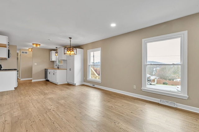 kitchen featuring a notable chandelier, decorative light fixtures, light wood-type flooring, and white cabinetry