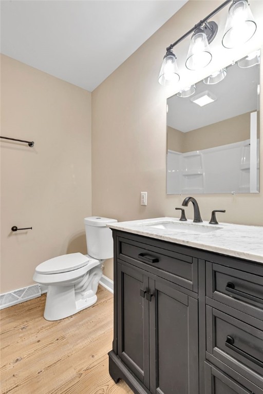 bathroom with a shower, vanity, wood-type flooring, and toilet