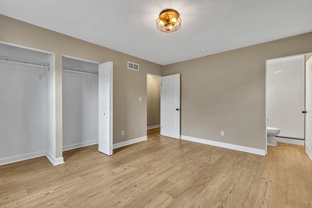 unfurnished bedroom with two closets, light hardwood / wood-style floors, and ensuite bath