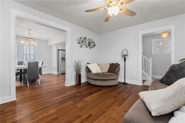 living room with dark wood-type flooring and ceiling fan with notable chandelier