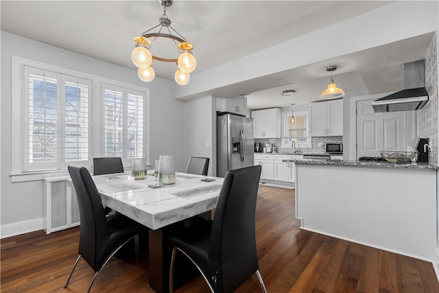 dining room featuring sink, dark wood-type flooring, and a notable chandelier