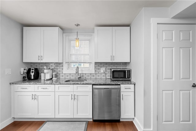 kitchen featuring white cabinets, hanging light fixtures, sink, appliances with stainless steel finishes, and wood-type flooring