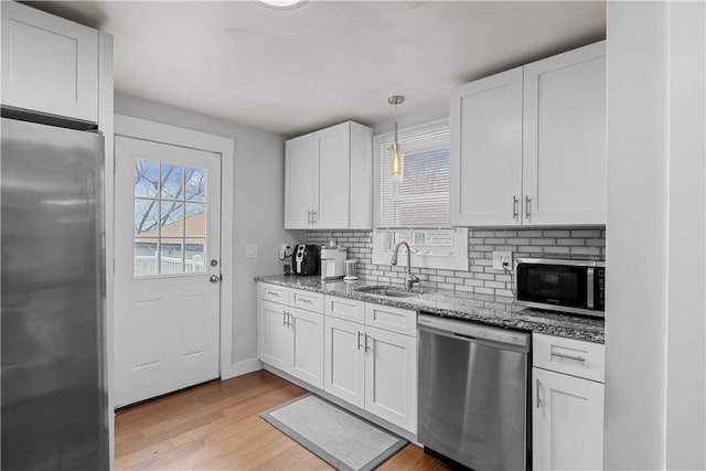 kitchen with white cabinetry, sink, hanging light fixtures, light hardwood / wood-style floors, and appliances with stainless steel finishes