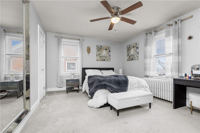 bedroom featuring ceiling fan, light colored carpet, radiator heating unit, and multiple windows