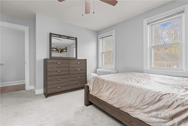 carpeted bedroom featuring radiator heating unit, multiple windows, and ceiling fan