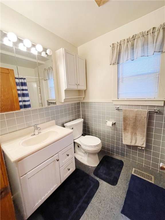 bathroom with curtained shower, vanity, tile walls, and toilet