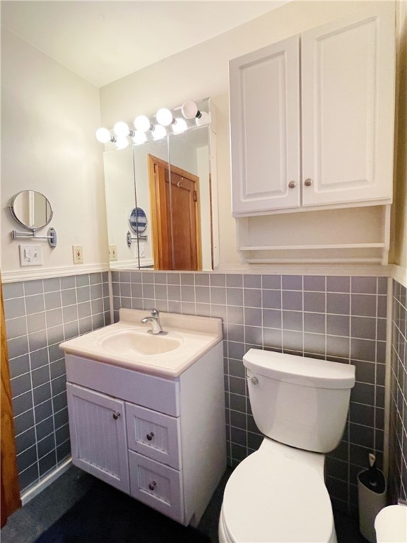 bathroom featuring vanity, tile walls, and toilet