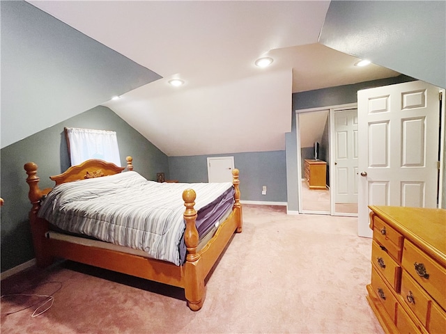 bedroom featuring lofted ceiling, light carpet, and a closet