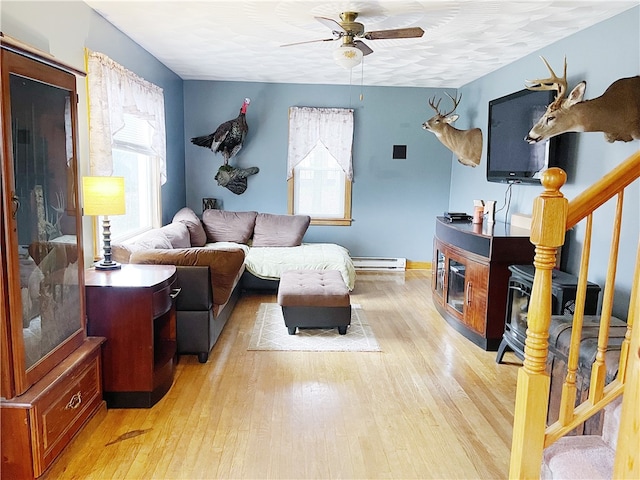 living room with ceiling fan, baseboard heating, and light hardwood / wood-style flooring