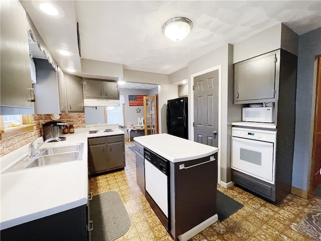 kitchen featuring backsplash, gray cabinetry, white appliances, sink, and a center island