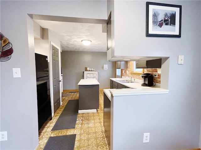 kitchen featuring a textured ceiling, a center island, kitchen peninsula, and sink