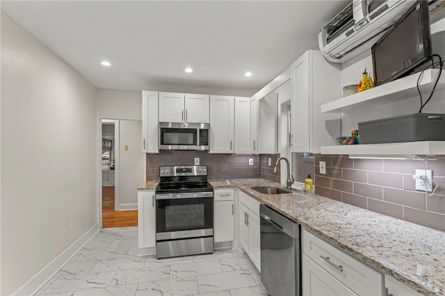 kitchen with sink, appliances with stainless steel finishes, white cabinetry, light stone countertops, and decorative backsplash