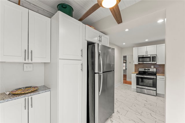 kitchen featuring light stone counters, white cabinets, ceiling fan, stainless steel appliances, and backsplash