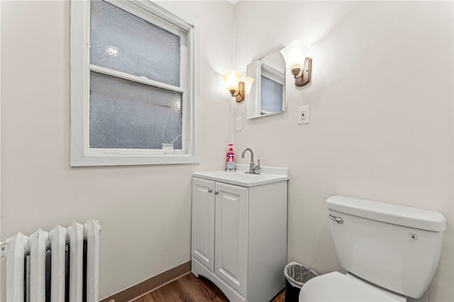 bathroom featuring vanity, hardwood / wood-style floors, radiator heating unit, and toilet