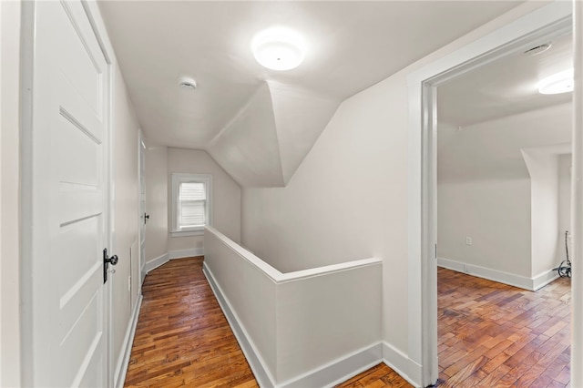 corridor with dark hardwood / wood-style flooring and vaulted ceiling