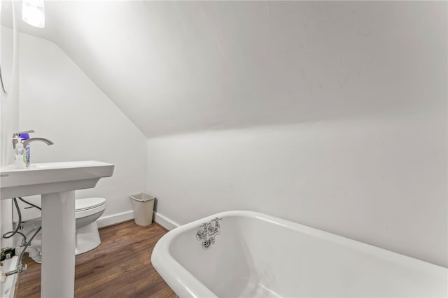 bathroom featuring lofted ceiling, a bathtub, toilet, and hardwood / wood-style flooring