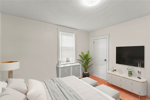 bedroom featuring light hardwood / wood-style floors and a textured ceiling