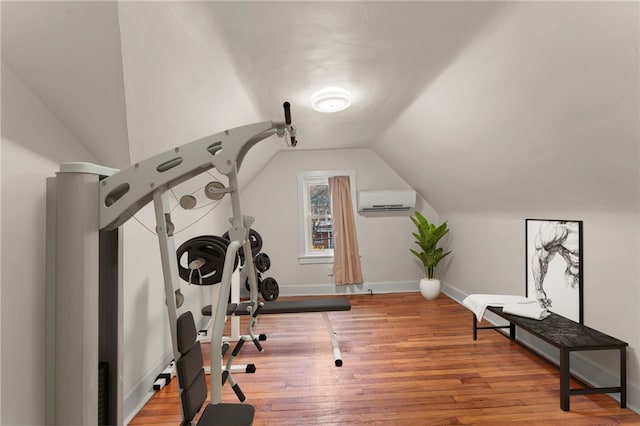 exercise room with a wall unit AC, lofted ceiling, and light hardwood / wood-style flooring