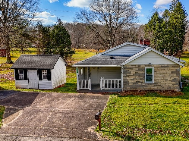 view of front of home featuring a front yard, a porch, and an outdoor structure