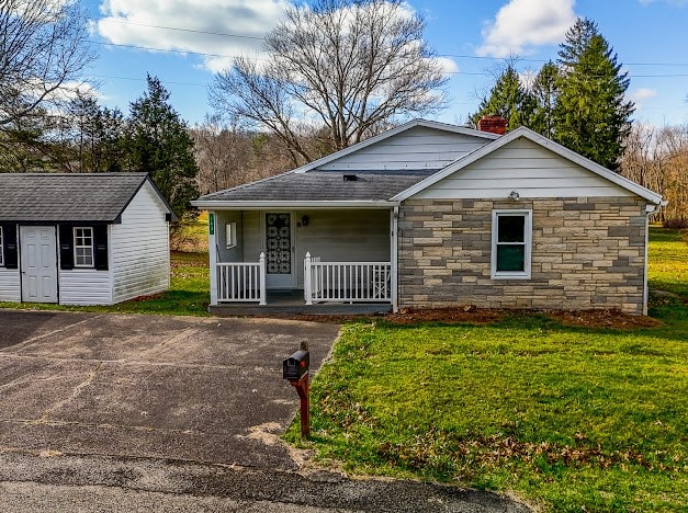 view of front of home featuring covered porch, an outbuilding, and a front lawn