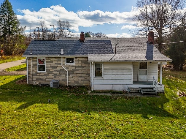 rear view of property featuring a yard and central AC