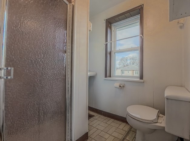 bathroom with a shower with shower door and toilet