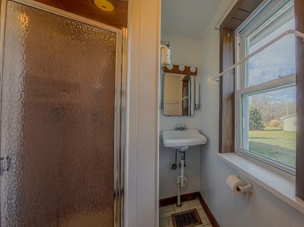 bathroom featuring a shower with door and sink