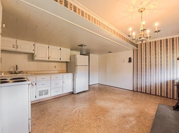 kitchen featuring white cabinetry, sink, a notable chandelier, pendant lighting, and white appliances