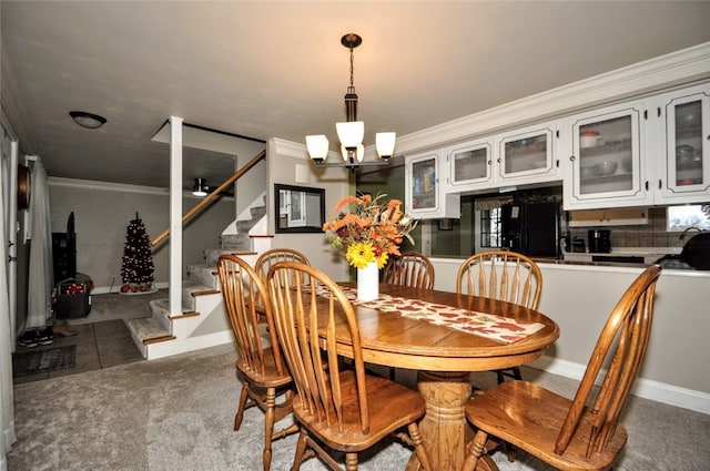 dining room featuring dark colored carpet, crown molding, and an inviting chandelier