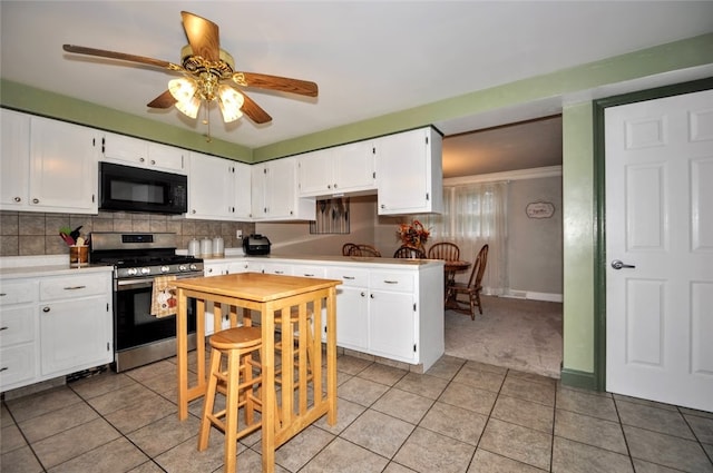 kitchen with white cabinets, ceiling fan, light tile patterned floors, and stainless steel gas range