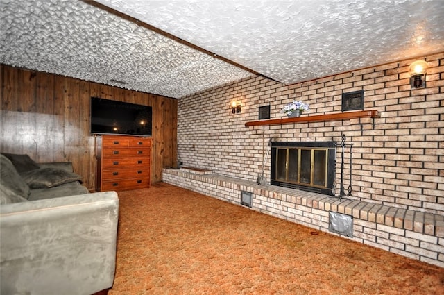 living room featuring carpet, a textured ceiling, a fireplace, and wood walls