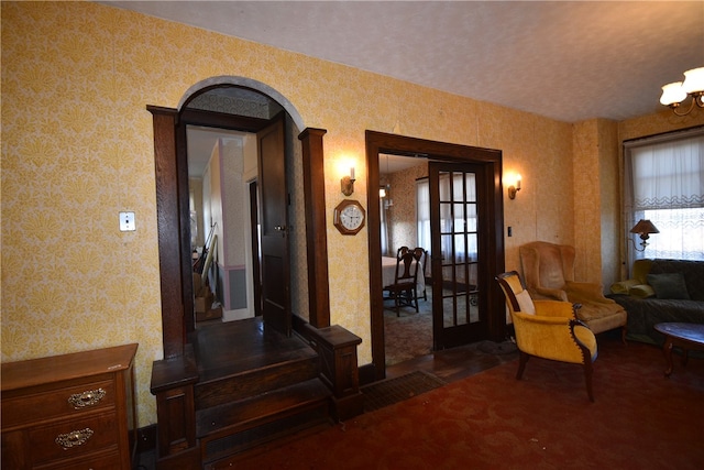 living area featuring french doors, dark carpet, and a notable chandelier