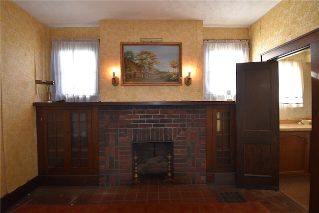 unfurnished living room with a wealth of natural light and a brick fireplace