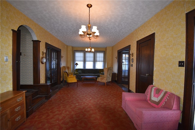 living room featuring dark carpet, a textured ceiling, and an inviting chandelier