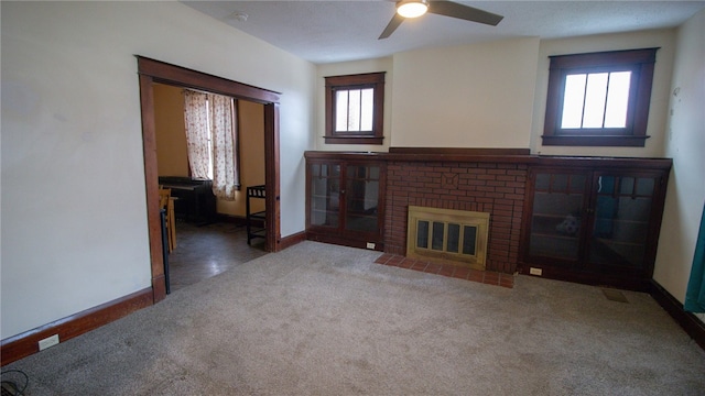 unfurnished living room featuring carpet, a fireplace, ceiling fan, and a healthy amount of sunlight