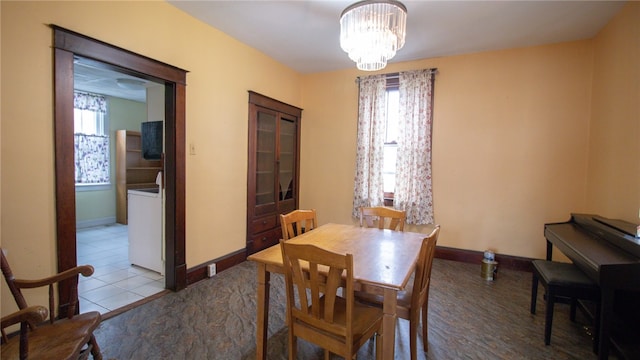 dining space featuring washer / dryer, tile patterned floors, and a notable chandelier