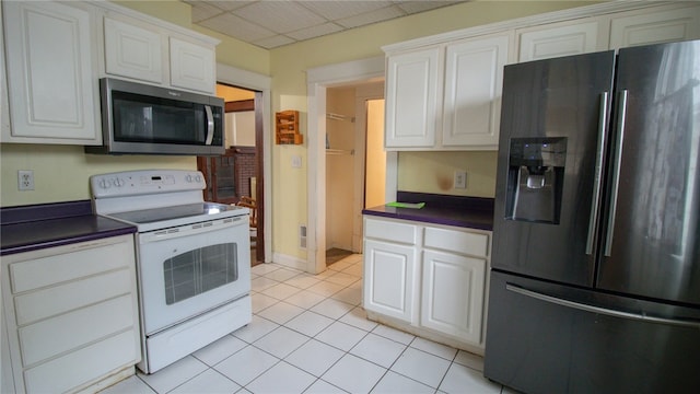 kitchen with white cabinets, light tile patterned flooring, and appliances with stainless steel finishes