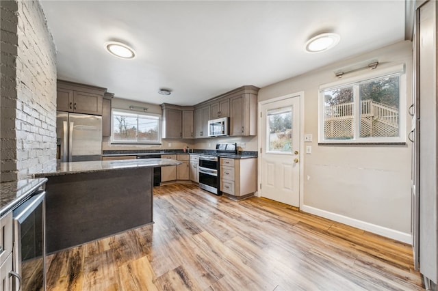 kitchen featuring wine cooler, dark stone countertops, light wood-type flooring, and appliances with stainless steel finishes