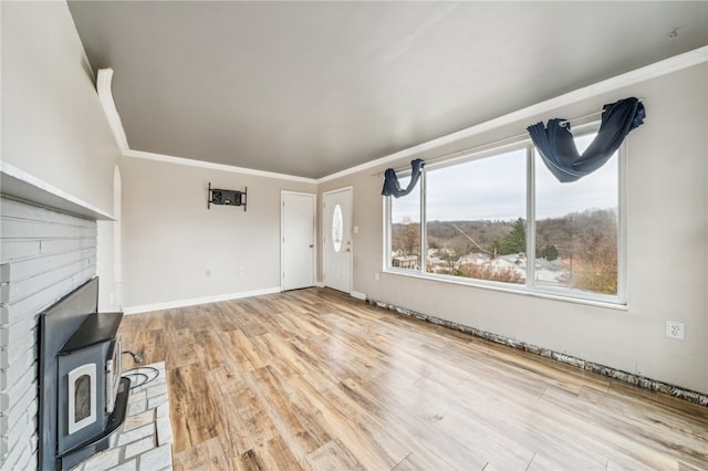 unfurnished living room with a wood stove, crown molding, and light hardwood / wood-style flooring