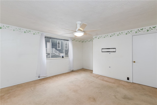 empty room featuring ceiling fan, a textured ceiling, and light carpet