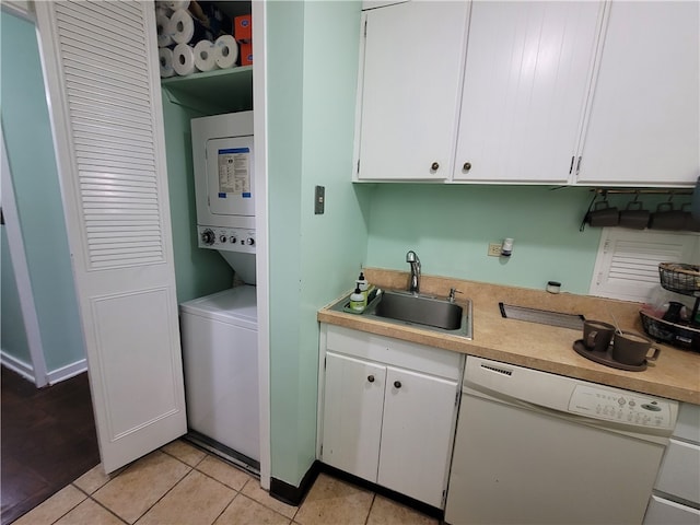 washroom with light tile patterned floors, stacked washer / dryer, and sink