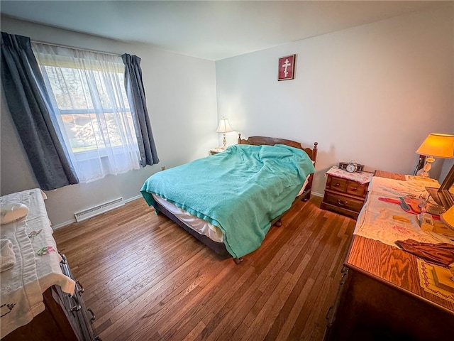 bedroom featuring dark hardwood / wood-style flooring and a baseboard heating unit