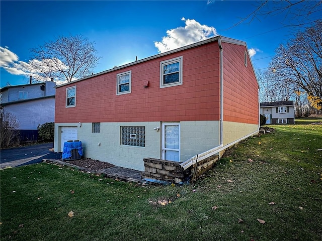 back of property featuring a garage and a lawn