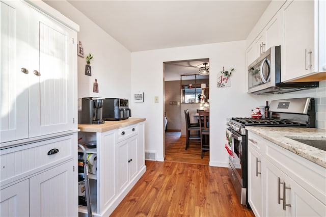 kitchen featuring light stone countertops, stainless steel appliances, white cabinetry, and light hardwood / wood-style flooring