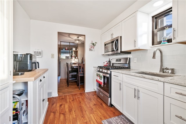 kitchen featuring white cabinetry, sink, stainless steel appliances, and light hardwood / wood-style floors