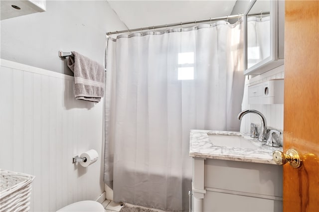 full bathroom featuring wooden walls, shower / tub combo with curtain, vanity, and toilet