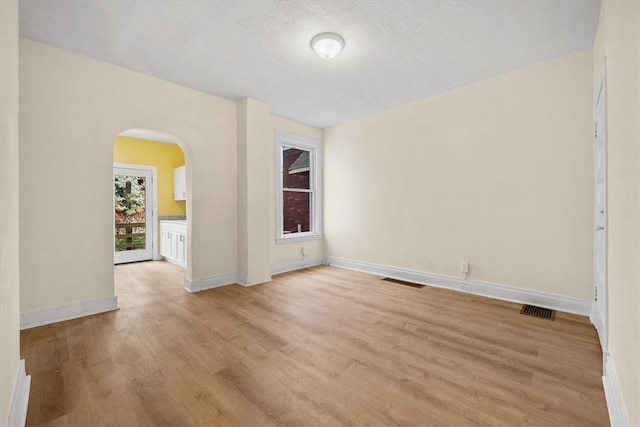 empty room with light hardwood / wood-style floors and a textured ceiling