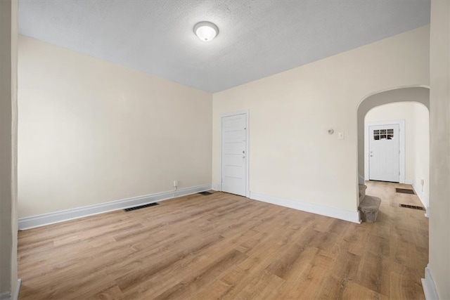 empty room featuring a textured ceiling and light hardwood / wood-style floors