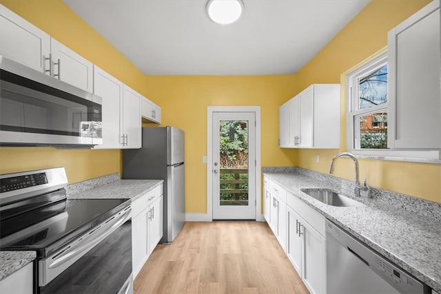 kitchen with sink, light wood-type flooring, light stone counters, white cabinetry, and stainless steel appliances