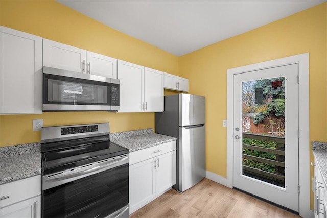 kitchen featuring light wood-type flooring, stainless steel appliances, white cabinetry, and light stone counters